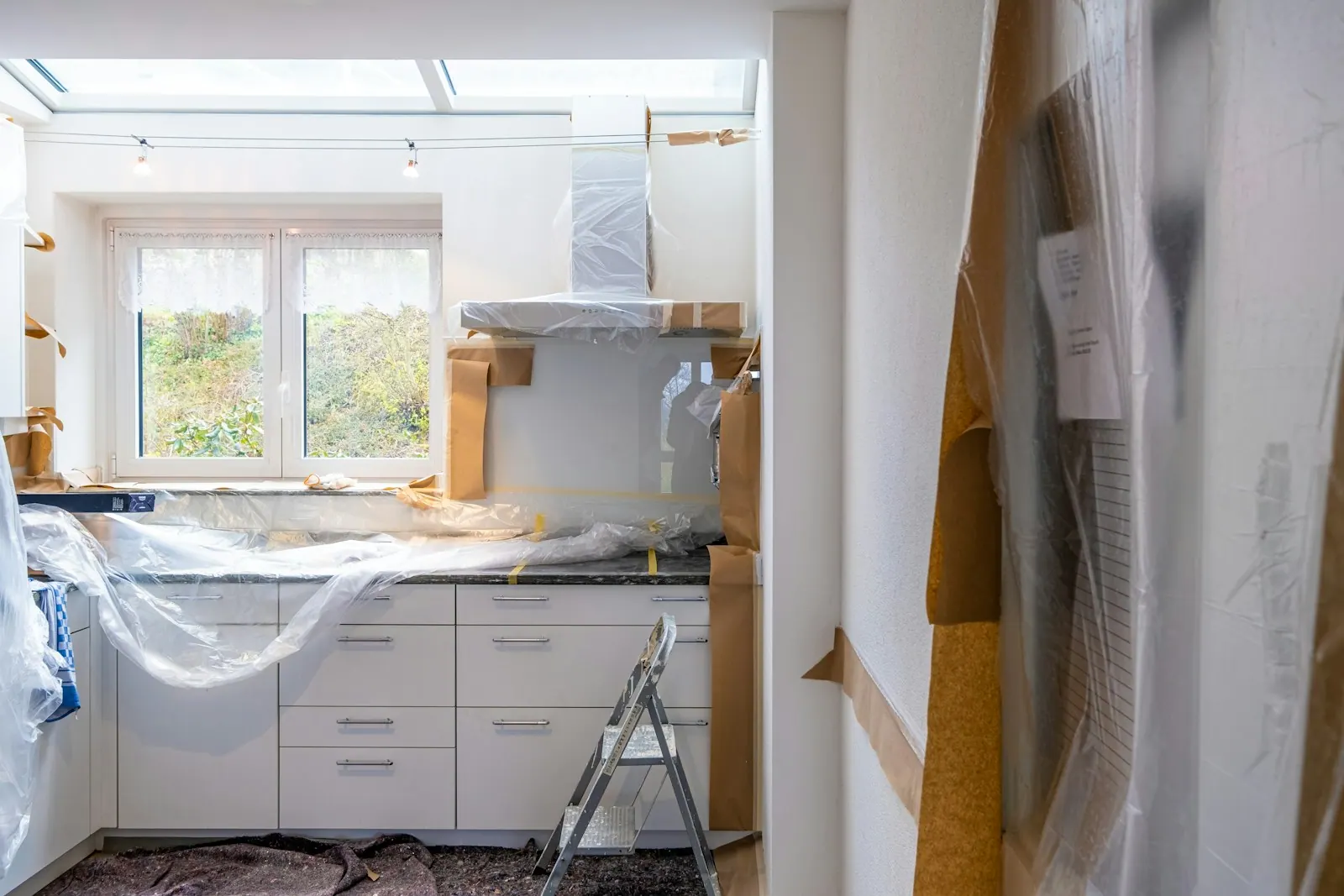 Kitchen renovation in progress with white cabinetry near a window