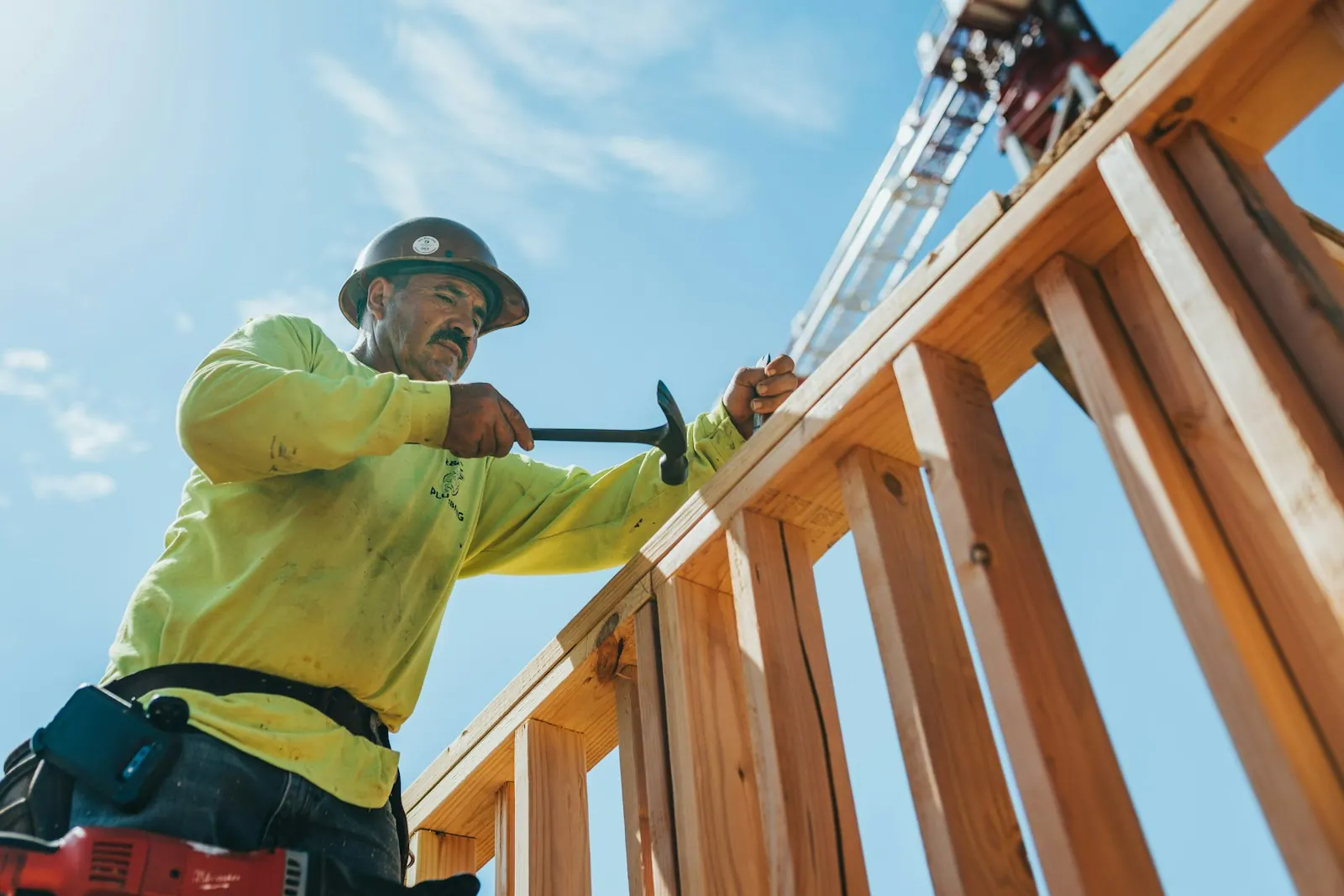 Contractor in a hard hat working on wood framing at a residential jobsite